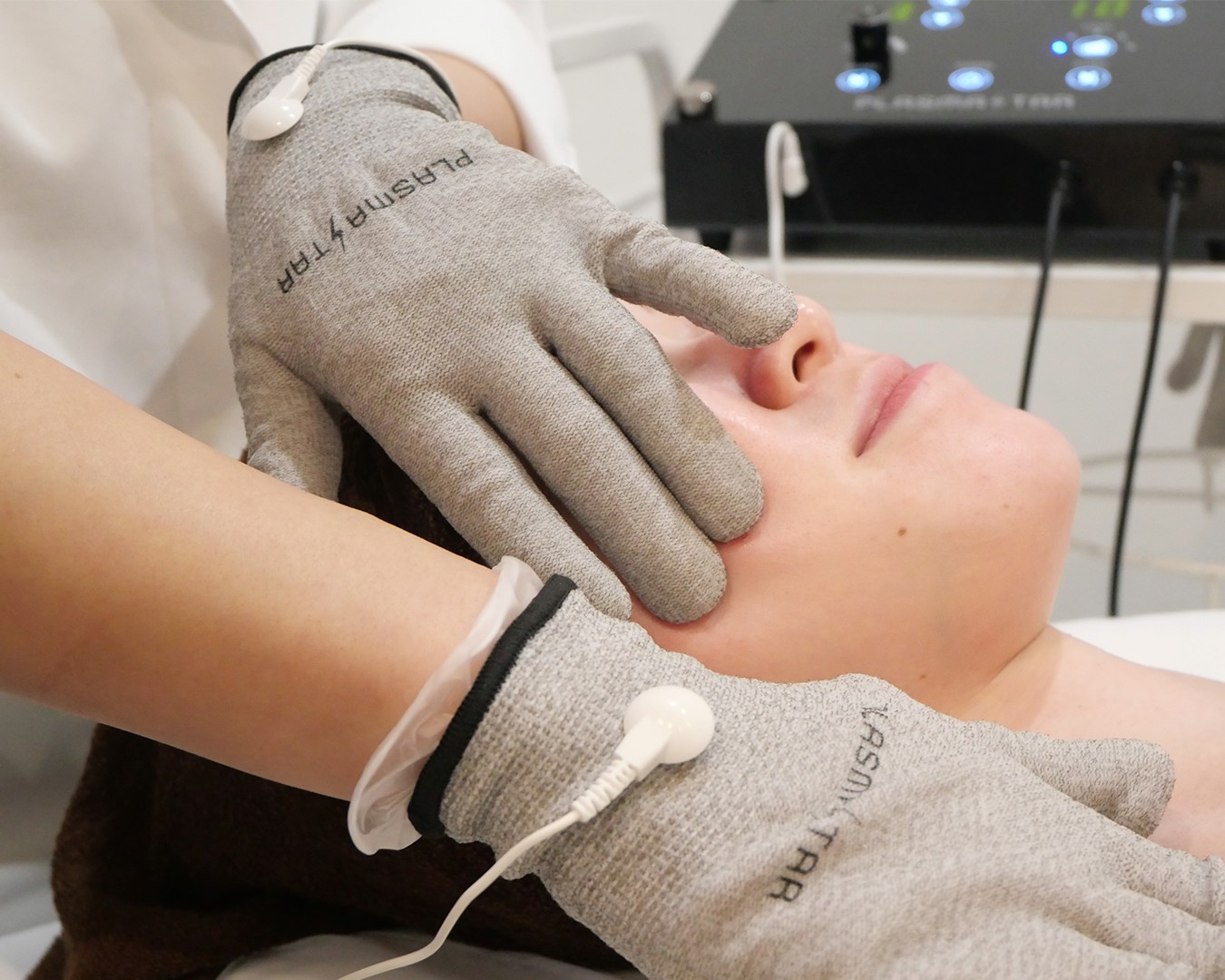 プラズマスターの専用グローブによるフェイス施術の様子(手袋型オールハンドで肌へなじませる)